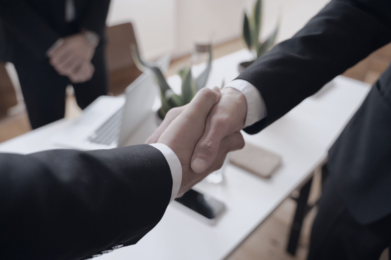 Handschlag zweier Geschäftspartner über einem Schreibtisch