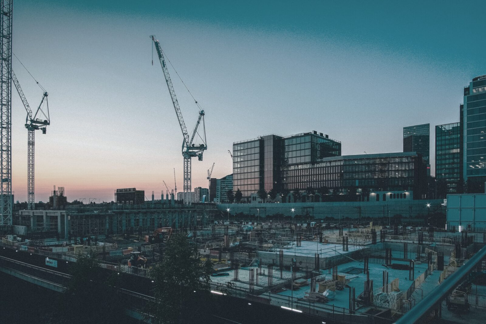 Baukräne und Großbaustelle in der Abenddämmerung